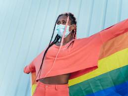 young gay black woman holding pride banner, LGBTQ