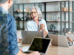 Happy mature old female mentor coach supervisor training young interns at group office meeting professional workshop, menopause