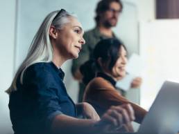 Senior woman with colleagues sitting by during business presentation, menopause, inclusion