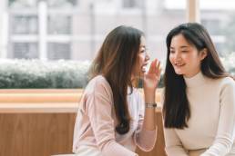 Asian pretty woman chat and gossip someone with her friend in coffee shop, pay rise, secrecy