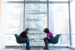 Ethnic minority individuals, two women sitting at a table on laptops, diversity