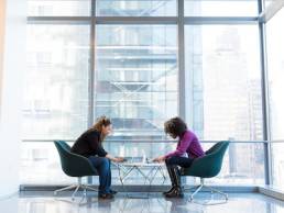 Ethnic minority individuals, two women sitting at a table on laptops, diversity