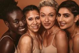 Portrait of four young women with different skin types. Diverse group of females standing together and looking at camera, beauty industry