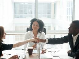 Smiling african businessman handshaking greeting caucasian businesswoman at group meeting negotiation, black satisfied entrepreneur welcoming partner shaking hand in lawyers office, respect concept, mediator