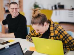 man and woman laughing while at work on laptops, Employee Appreciation Day, thanks