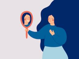 Young woman looks at the mirror and sees her happy reflection. Self-acceptance and confidence concept.
