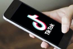 Man holding a smartphone with TikTok app open