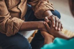 Female carer holding hands of senior man