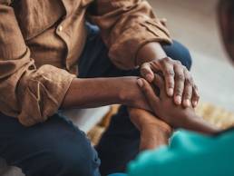 Female carer holding hands of senior man