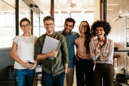 Portrait of creative business team standing together and laughing. Multiracial business people together at startup.