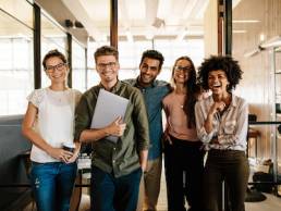 Portrait of creative business team standing together and laughing. Multiracial business people together at startup.