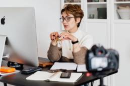 Confident elegant lady in eyeglasses hosting webinar