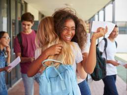 Two girls celebrating exam results in school corridor