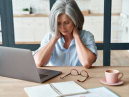 Tired stressed old mature business woman suffering from neckpain working from home office sitting at table. Overworked senior middle aged lady massaging neck feeling hurt pain from incorrect posture. Menopause