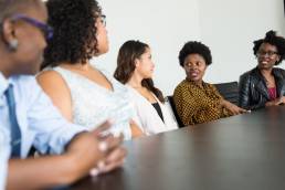 Diversity and inclusion, five colleagues sitting at table during meeting