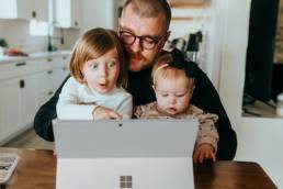 Man sitting at desk with his children, working from home, working parent, International men's day, working father