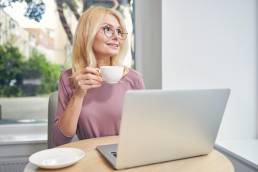 Happy mature woman sitting at computer, working at home