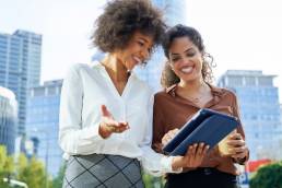 Two business women holding a digital tablet in the city