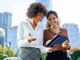 Two business women holding a digital tablet in the city