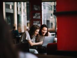 Flexible working, two female colleagues working together in cafe, hybrid working