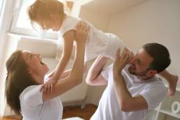 Happy mum and dad playing with daughter, maternity and paternity leave