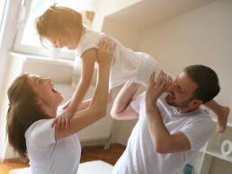 Happy mum and dad playing with daughter, maternity and paternity leave
