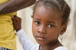 Portrait of African black little girl looking at camera and holding dad's shirt