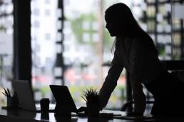 Businesswoman leaning over desk in office, working in property