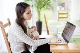 working mum, woman working at home with baby in her arms, returning to work