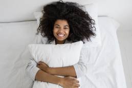 Smiling happy woman hugging pillow after having good night's sleep