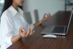 Yoga moves at the desk, stretches, woman sitting at desk practising meditation, wellbeing