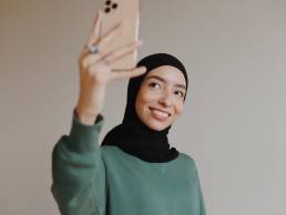 Smiling woman taking selfie, using social media to advance career