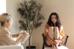 Sad woman sitting on chair during therpay session, mental health, negativity bias