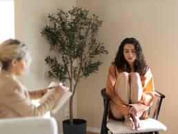 Sad woman sitting on chair during therpay session, mental health, negativity bias
