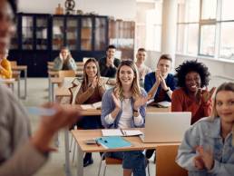 Group of happy students applauding to their lecturer while attending class at the university classroom.