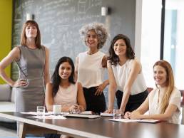 Five female colleagues at a work meeting smiling to camera