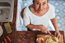 Smiling woman in kitchen, cutting vegetables, menopause, restoring balance