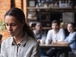 Upset mixed race woman suffering from bullying, discrimination, excluded girl having problem with bad friends, feeling offended and hurt, sitting alone in cafe, avoiding people, social outcast